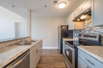 An empty kitchen with granite counter tops and stainless steel appliances